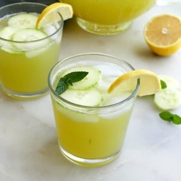 two glasses of cucumber mint lemonade in front of a pitcher