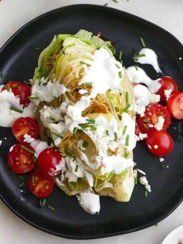 square image of grilled wedge salad with tomatoes and dressing on a plate