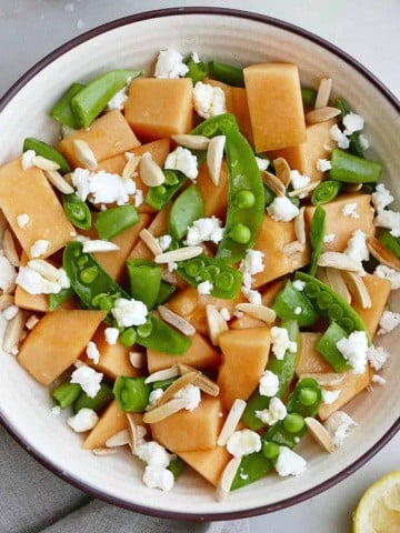 square image of melon and sugar snap pea salad in a bowl on a counter