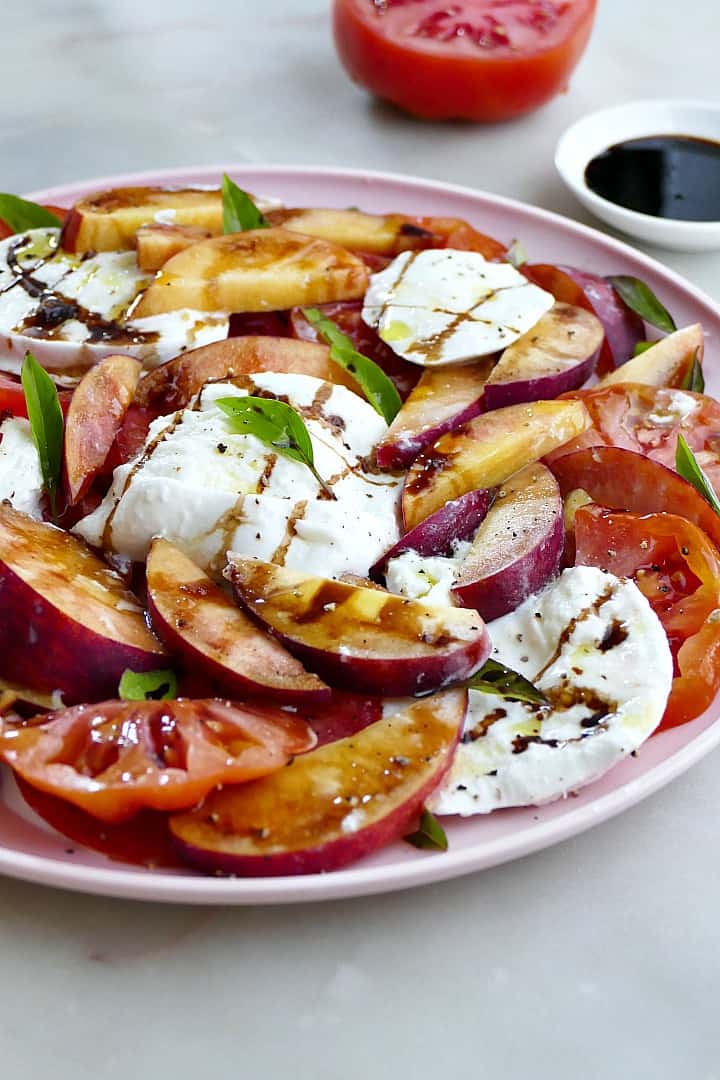 peach and tomato salad with mozzarella, balsamic, and basil on a platter