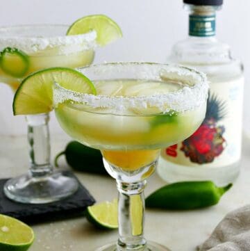 pineapple jalapeno margaritas on a counter garnished with salt rims and lime