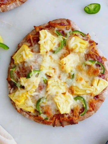 square image of pineapple jalapeno pizza on whole wheat pita bread on a counter