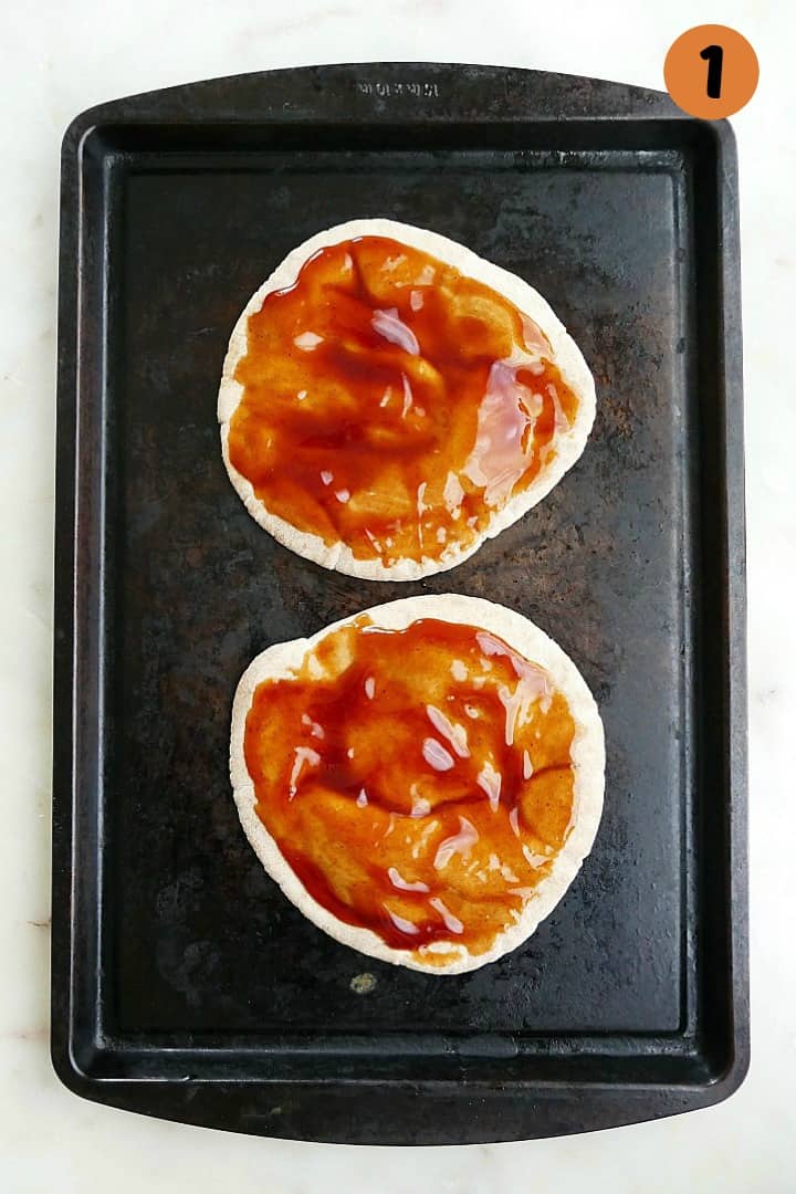 whole wheat pita on a baking sheet spread with bbq sauce