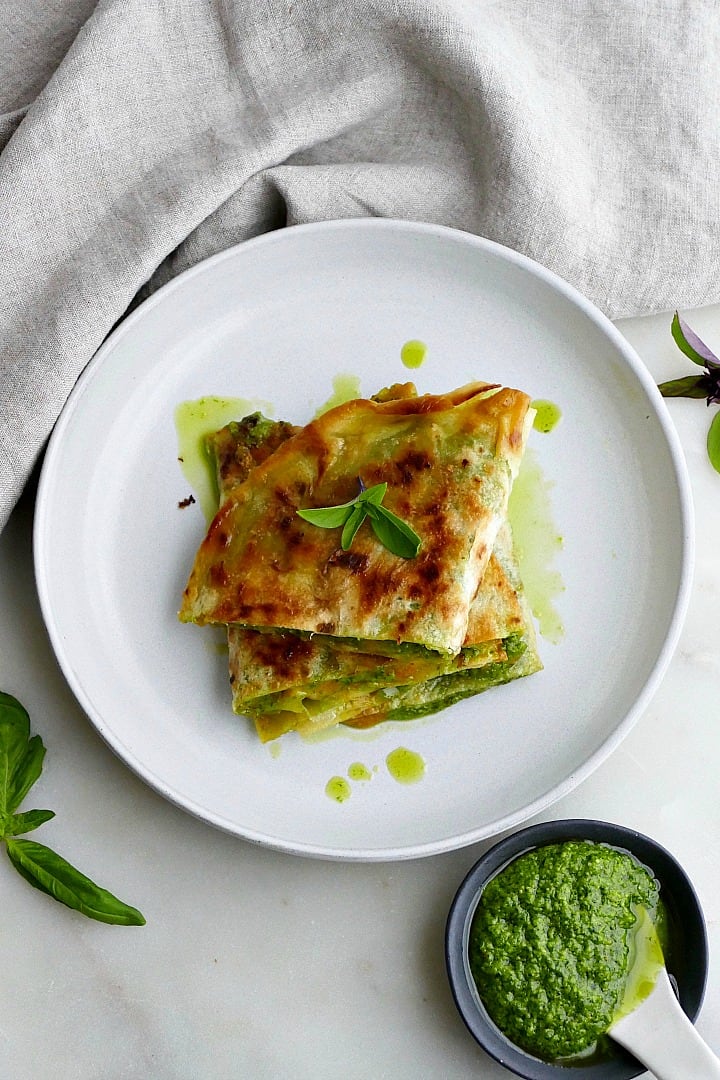 overhead shot of a sliced quesadilla on a plate garnished with basil leaves