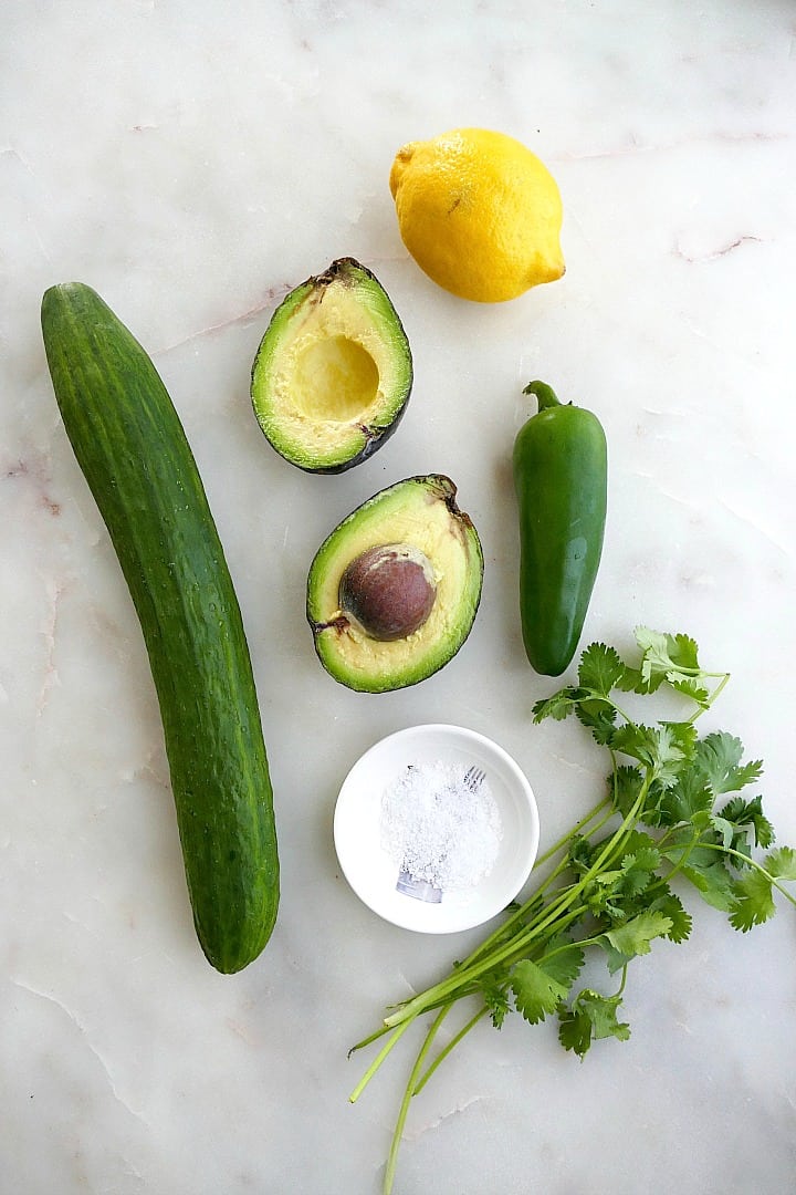 cucumber, avocado, lemon, jalapeno, salt, and cilantro spread out on a counter