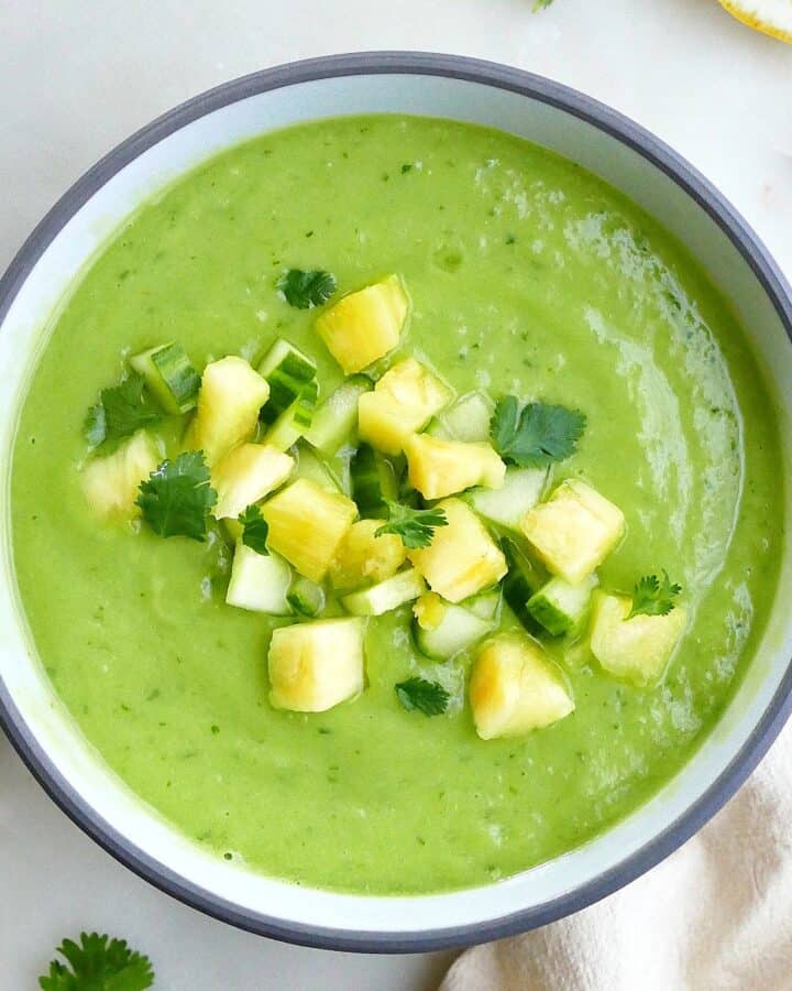 square image of a cucumber avocado soup with chopped pineapple on a counter