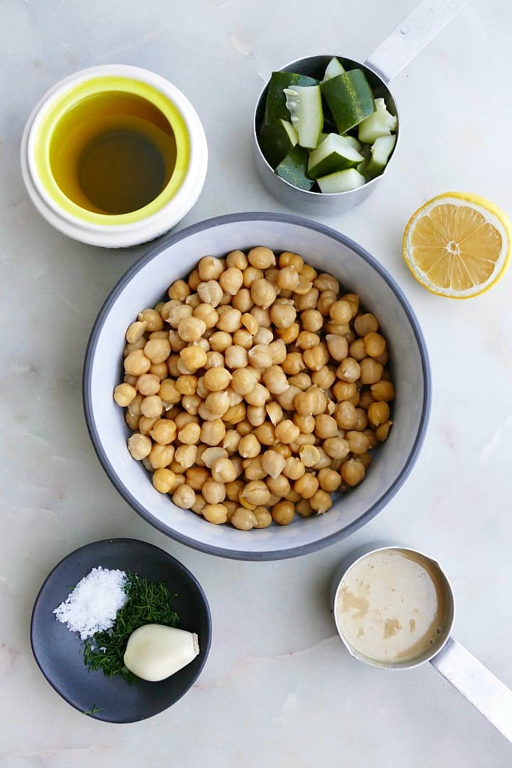 olive oil, pickles, garlic, spices, chickpeas, tahini, and lemon on a counter