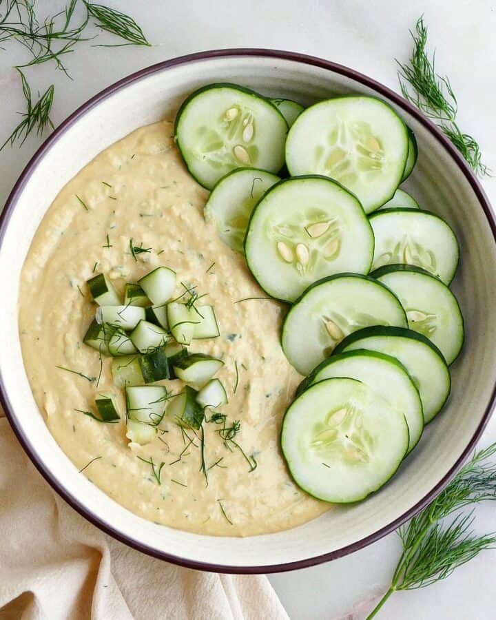 square image of dill pickle hummus garnished with cucumbers and dill