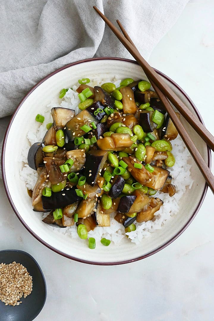 eggplant teriyaki stir fry in a serving dish with brown chopsticks on the edge