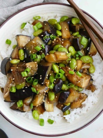 square image of eggplant teriyaki in a serving dish with brown chopsticks