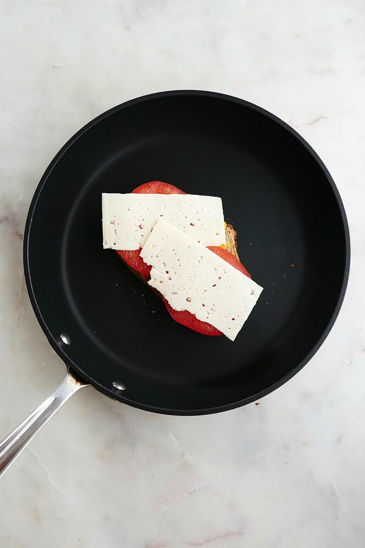 an open-faced grilled cheese in a black skillet on a counter