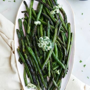 herb and garlic butter green beans displayed on an oval serving platter