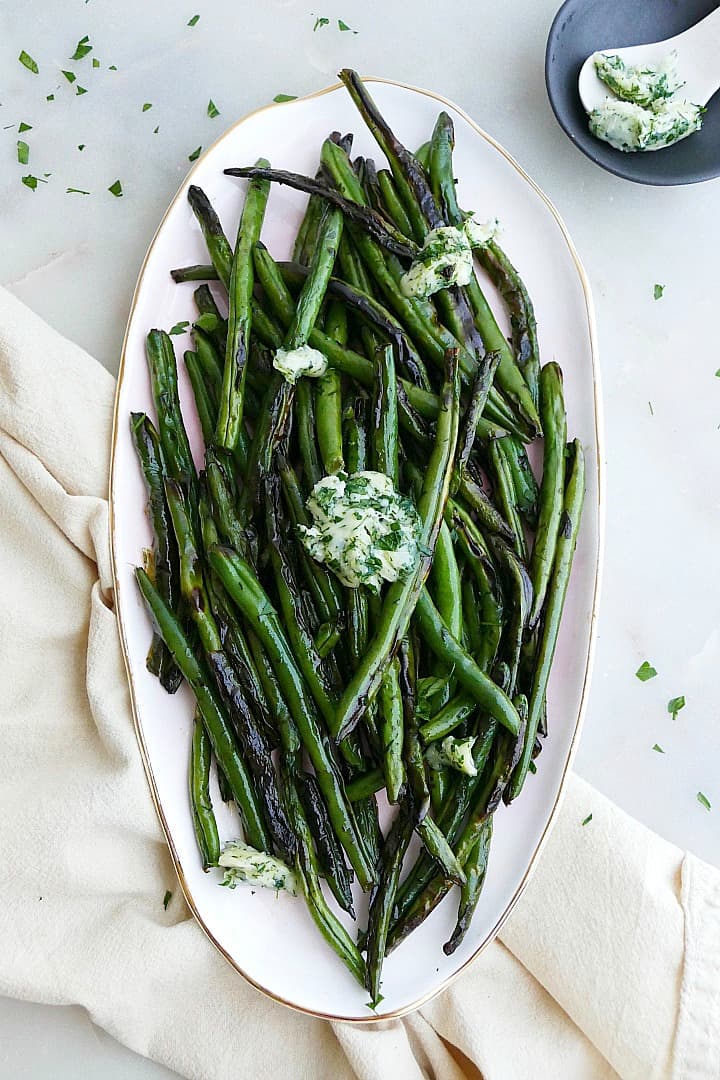 herb and garlic butter green beans displayed on an oval serving platter