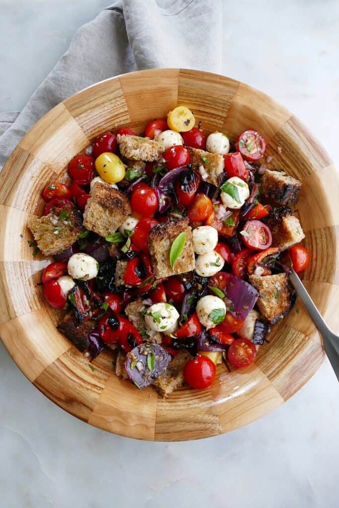 grilled panzanella salad in a wooden bowl with a serving spoon