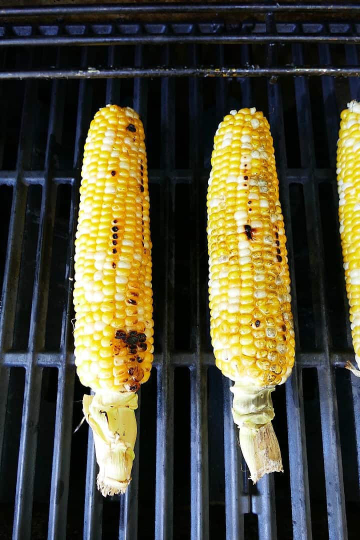 two cobs of corn on grill mats on top of an outdoor grill