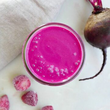 strawberry banana beet smoothie on a counter next to ingredients