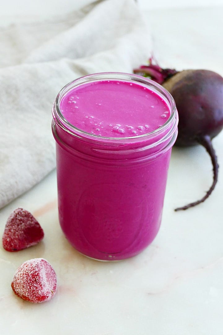 side view of strawberry banana beet smoothie in front of a napkin