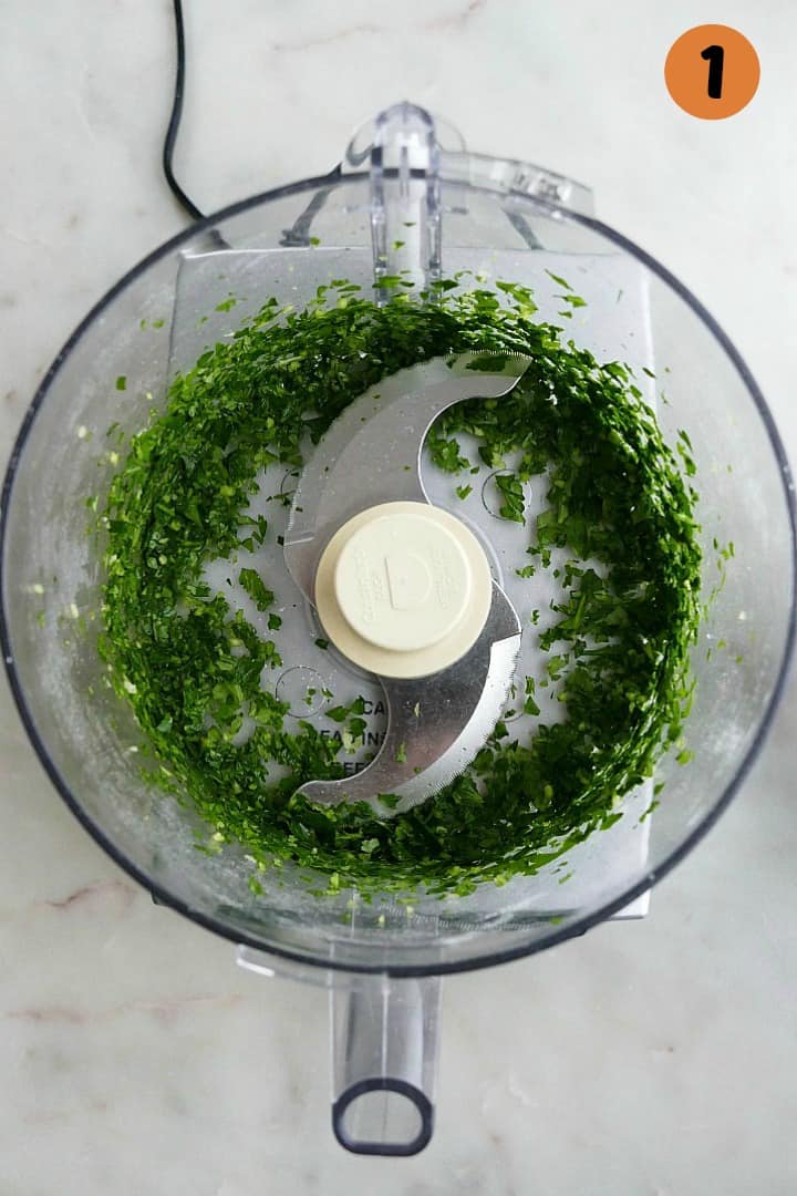 image of herbs in a food processor with the number one in the right corner