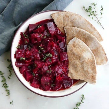 beetroot curry next to four slices of pita in a serving bowl on a counter
