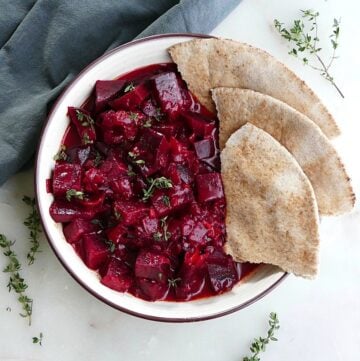beetroot curry next to four slices of pita in a serving bowl on a counter