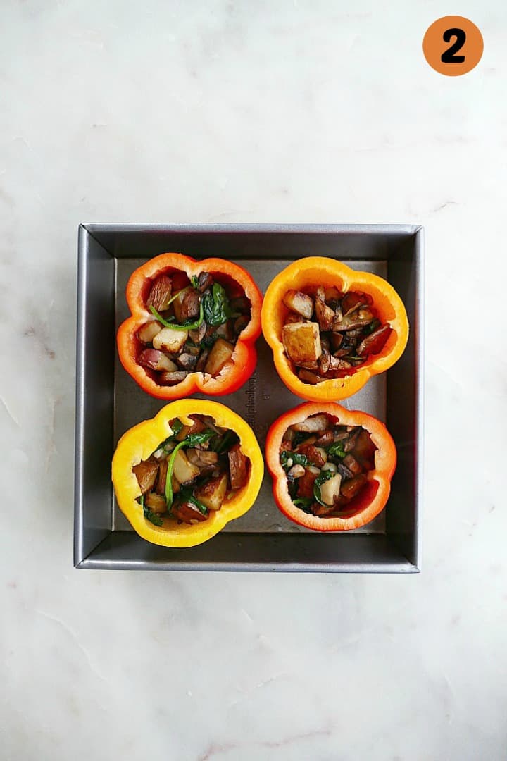 bell peppers stuffed with veggies in a baking dish on a counter with the number two in the corner