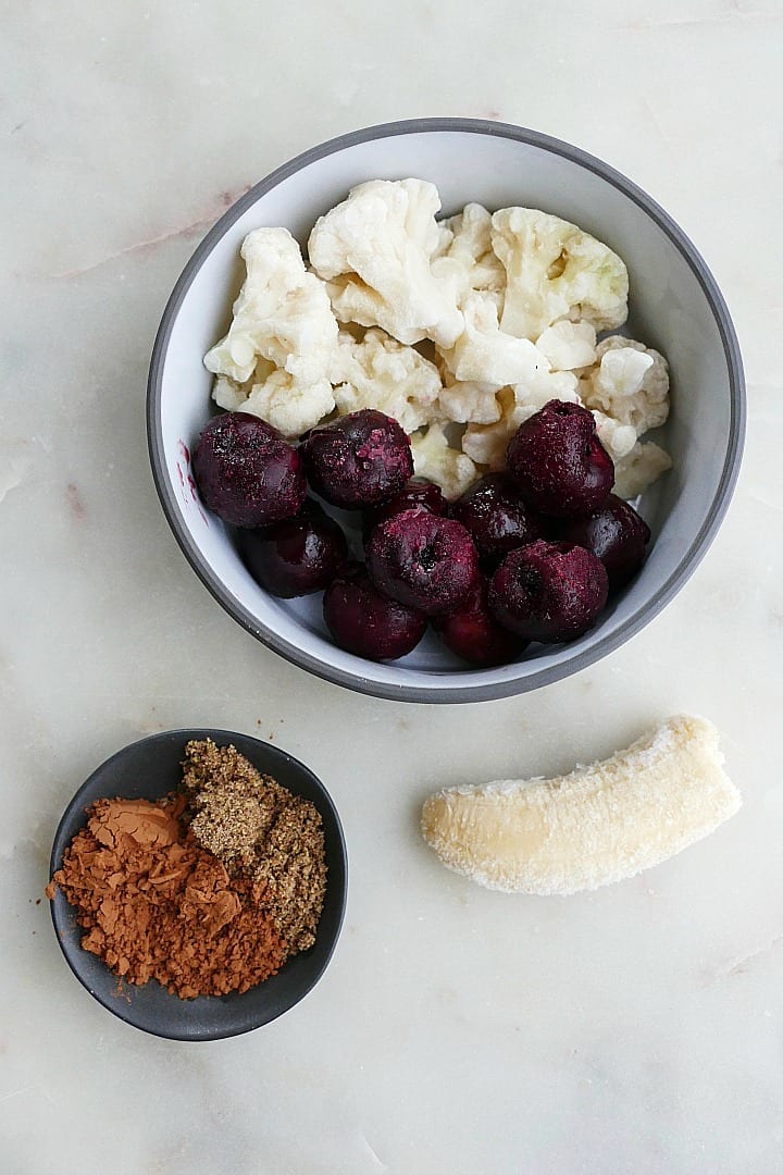 bowl of frozen cherries and cauliflower next to frozen banana and spices