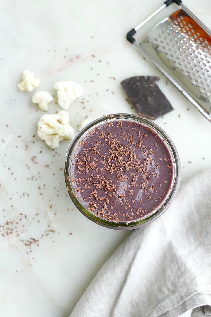 cherry chocolate cauliflower smoothie on a counter next to napkin and ingredients