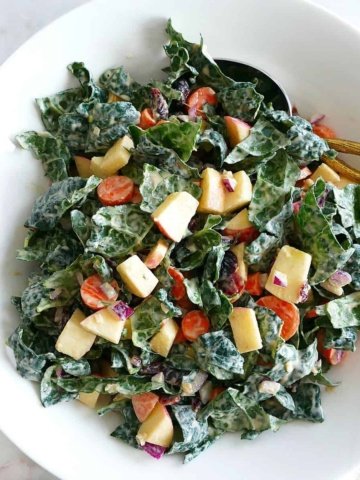 square image of kale salad with tahini dressing in a mixing bowl on a counter