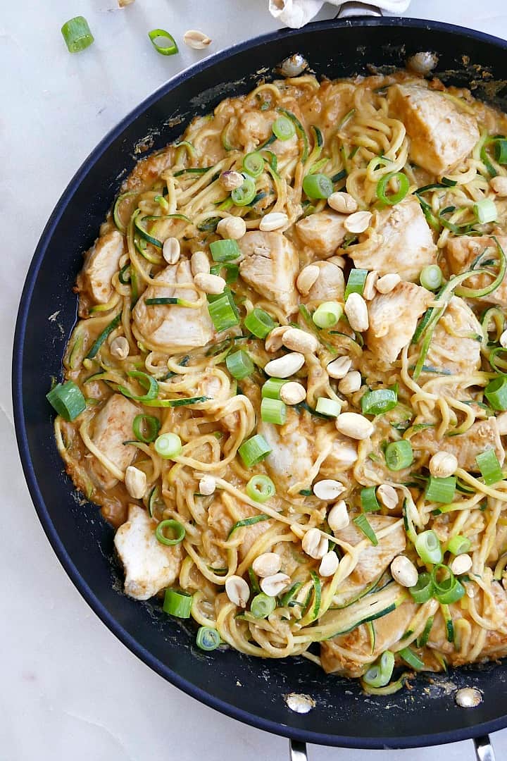 close up of peanut zoodles with chicken and scallions in a large skillet