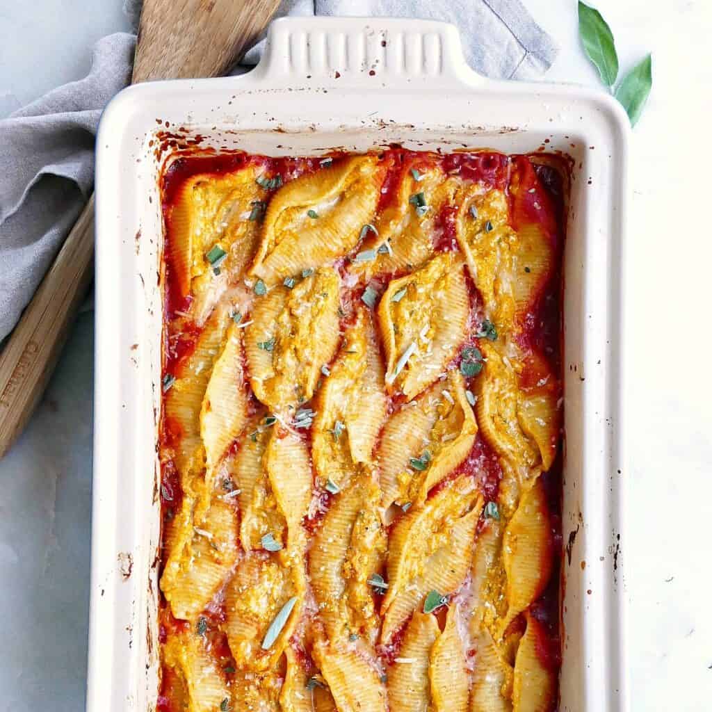 square image of pumpkin stuffed shells in a baking dish on a counter