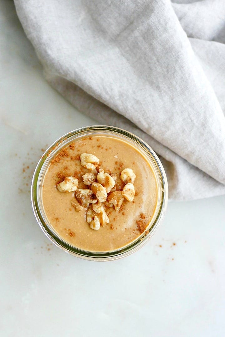 sweet potato smoothie topped with crushed walnuts next a napkin on a counter
