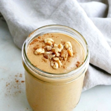 side view of sweet potato smoothie topped with walnuts and cinnamon on a counter