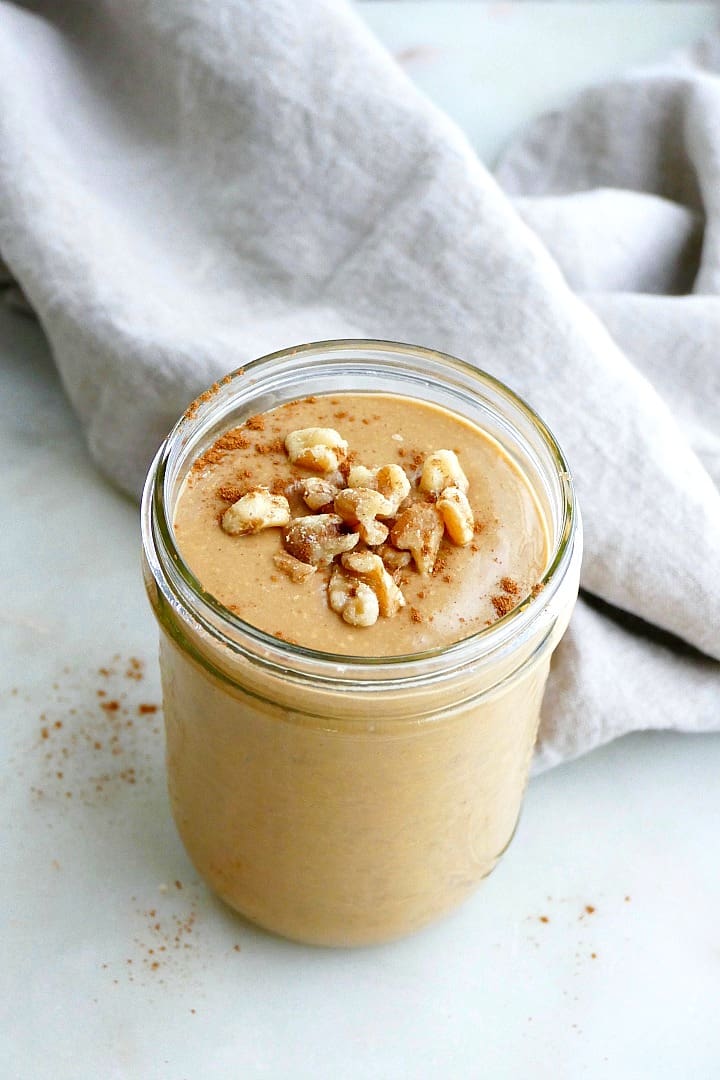 side view of sweet potato smoothie topped with walnuts and cinnamon on a counter
