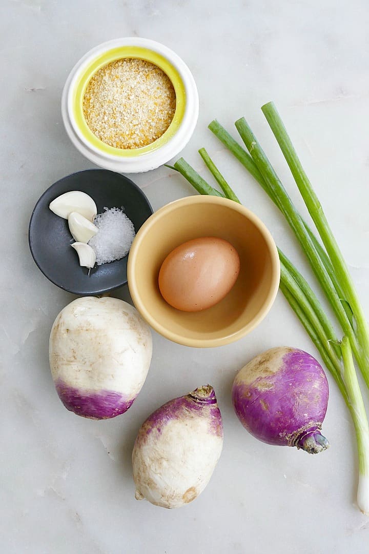 cornmeal, garlic, salt, turnips, egg, and scallions spread out on a counter