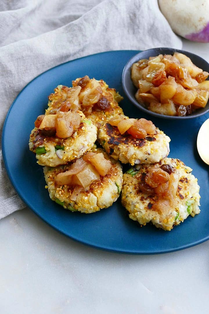 side view of five turnip hash brown cakes with apple chutney on a serving platter