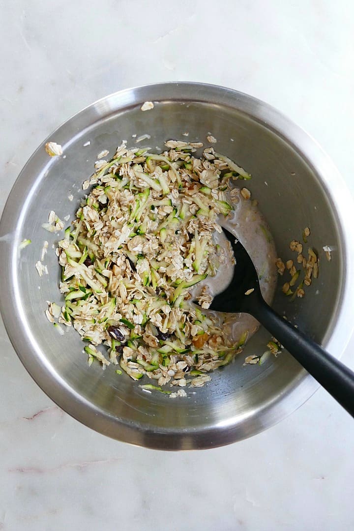 overnight oats mixture with shredded zucchini in a mixing bowl with a large spoon