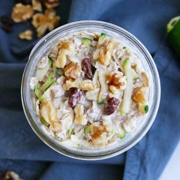 overhead shot of zucchini overnight oats in a jar topped with walnuts and raisins