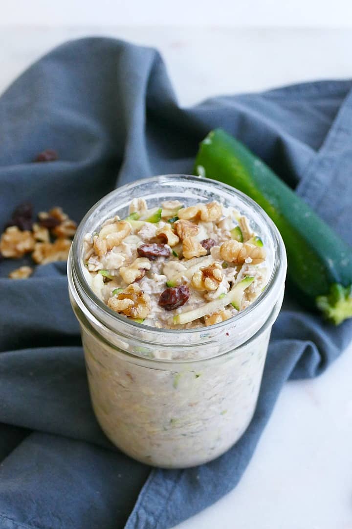 side shot of zucchini overnight oats in a jar topped with walnuts and raisins