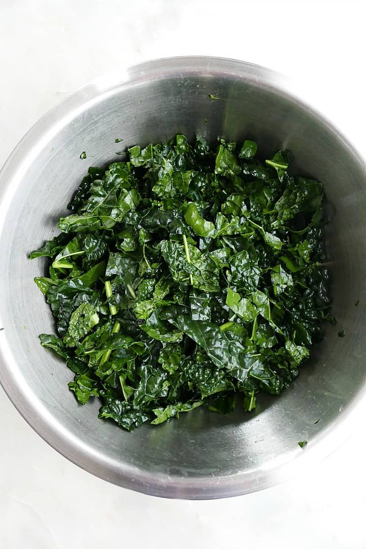 massaged lacinato kale in a large mixing bowl on a counter
