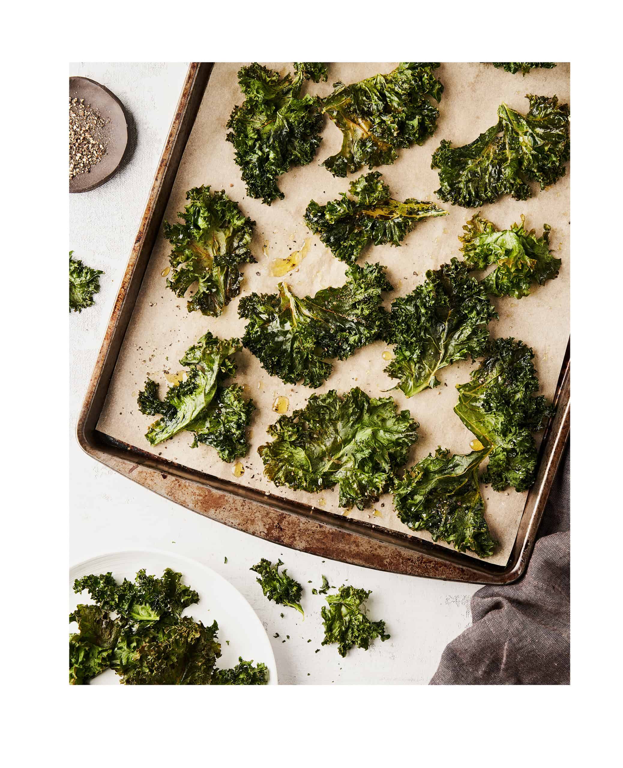 crispy kale chips on a baking sheet on a white counter