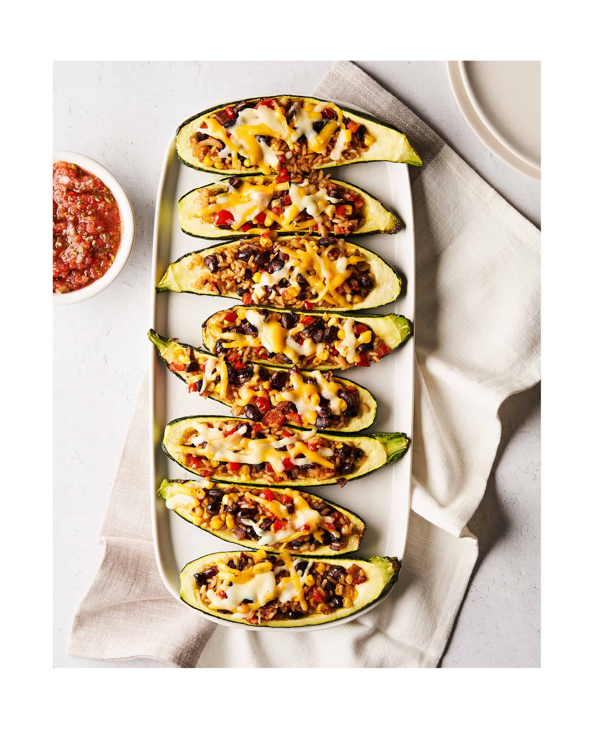 8 zucchini taco boats on a long serving plate on top of a napkin on a counter