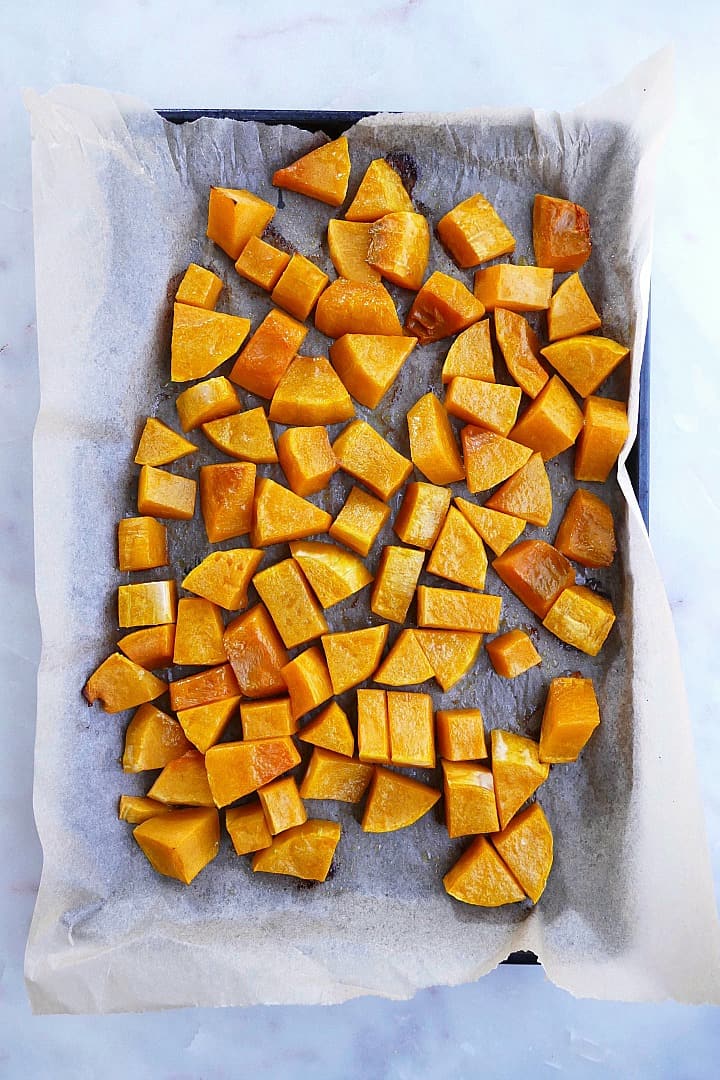 diced butternut squash cubes spread out on a baking sheet with parchment