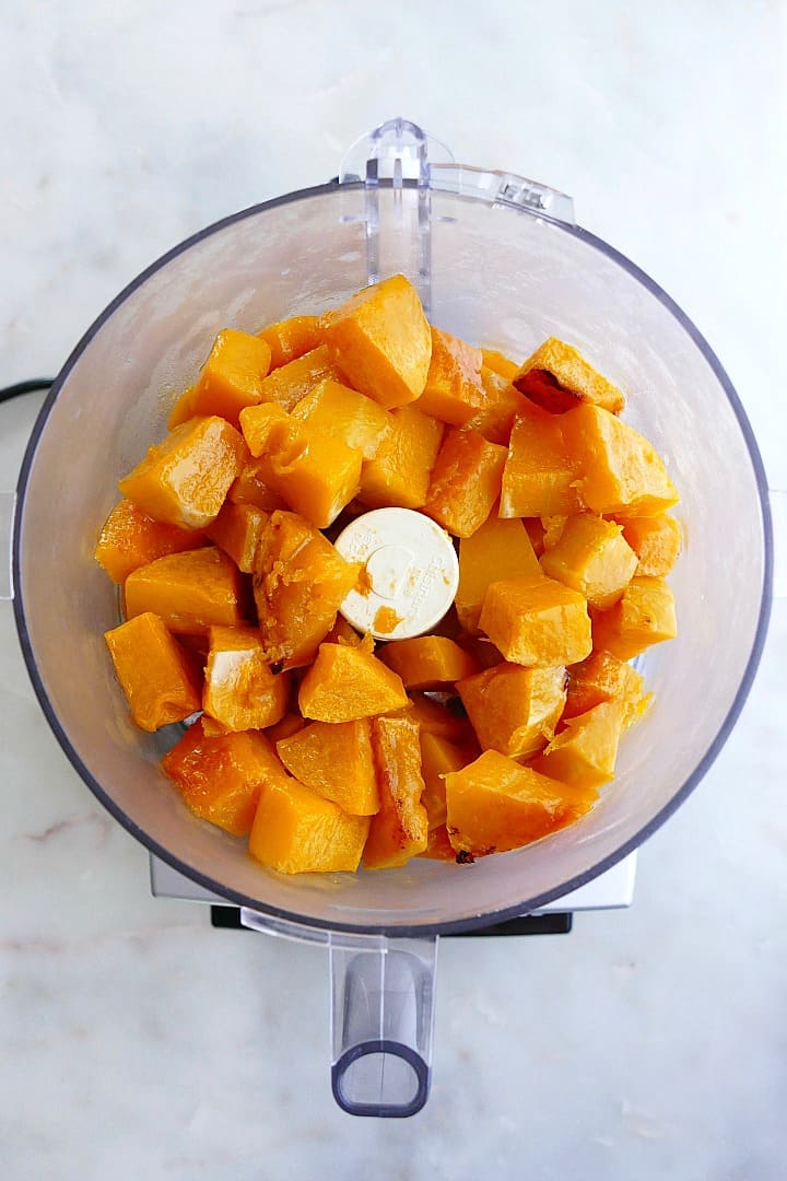 roasted butternut squash cubes in a food processor on a counter