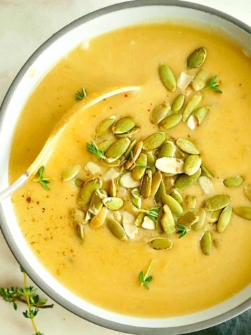 square image of butternut squash and pear soup topped with pepitas and thyme