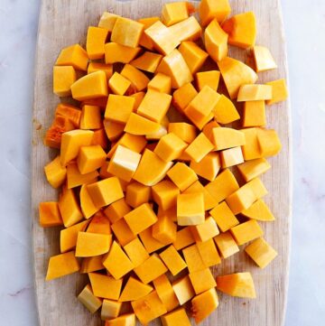 butternut squash cubes spread out on a cutting board on a counter
