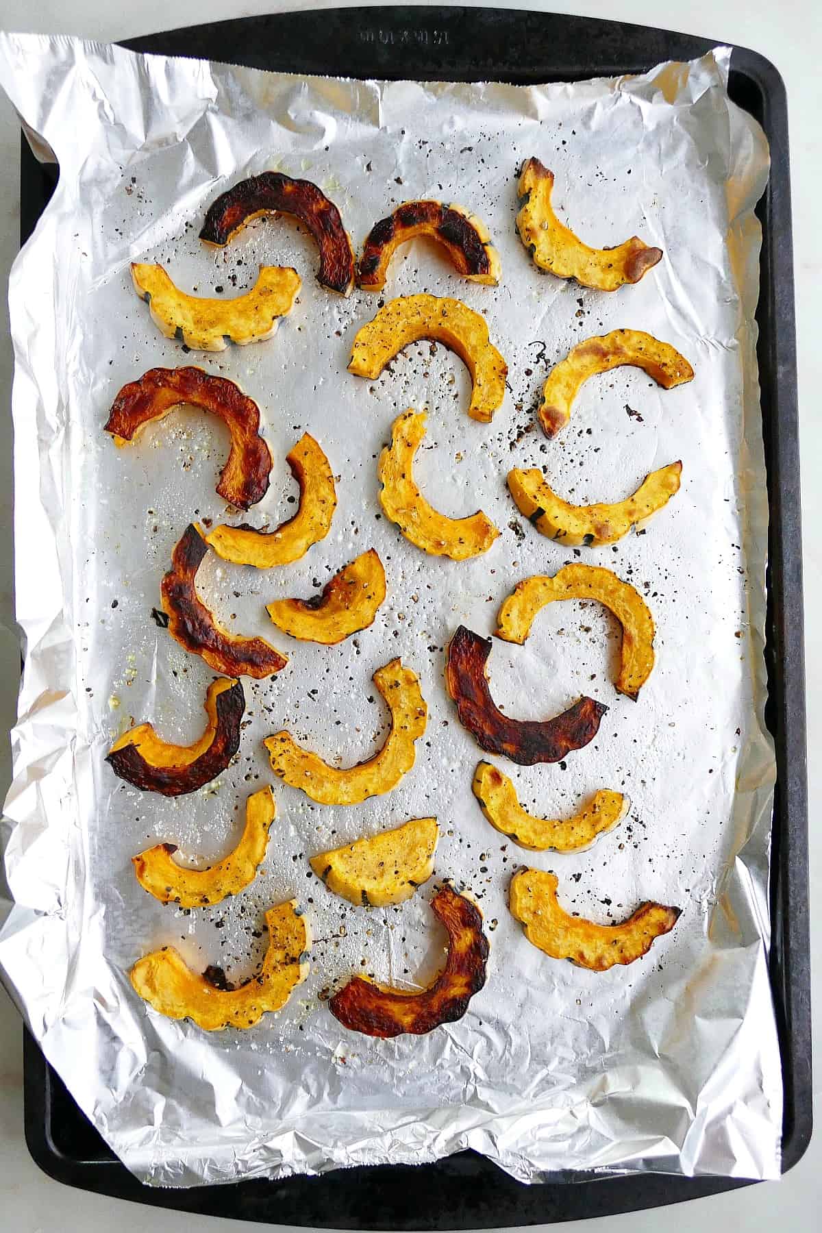 baked delicata squash fries on a baking sheet lined with aluminum foil