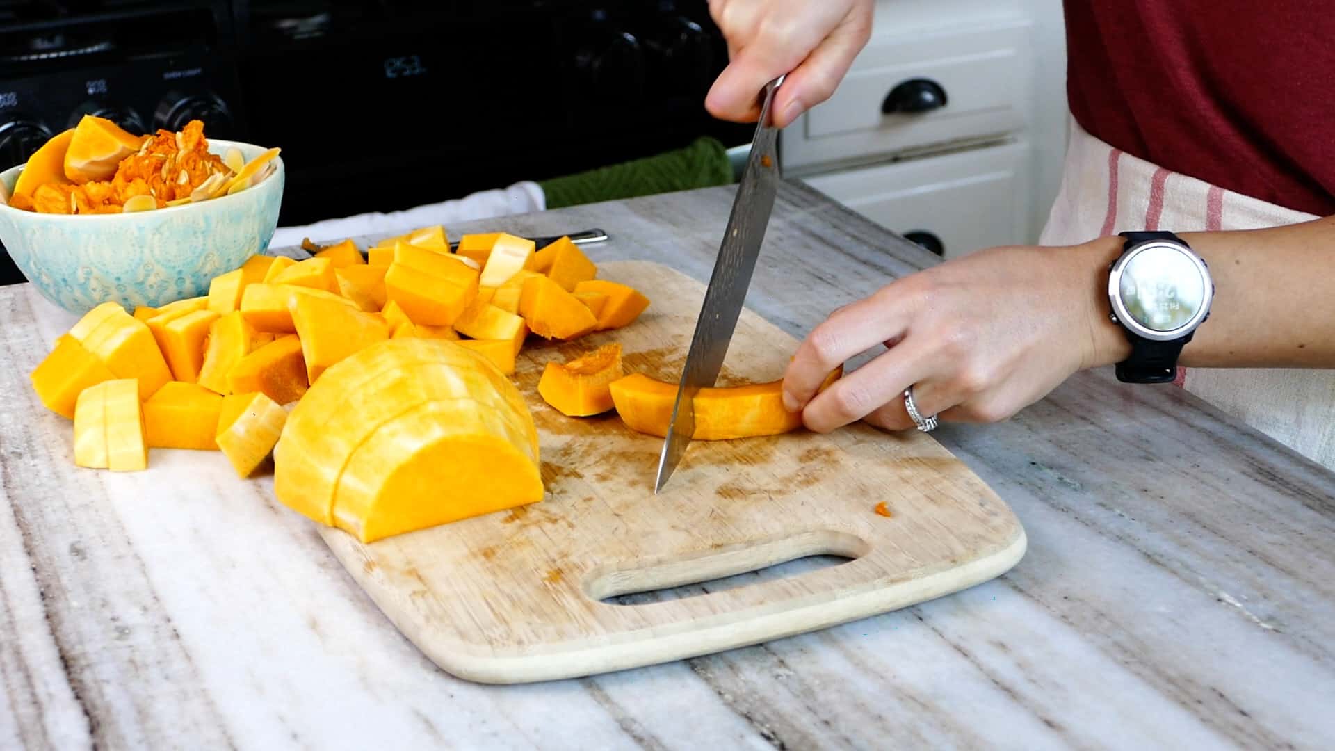 woman cutting butternut squash on a cutting board in a kitchen