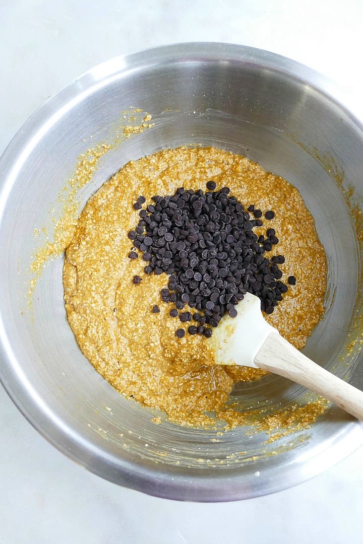 batter for pumpkin oatmeal bread in a mixing bowl with chocolate chips and a spatula