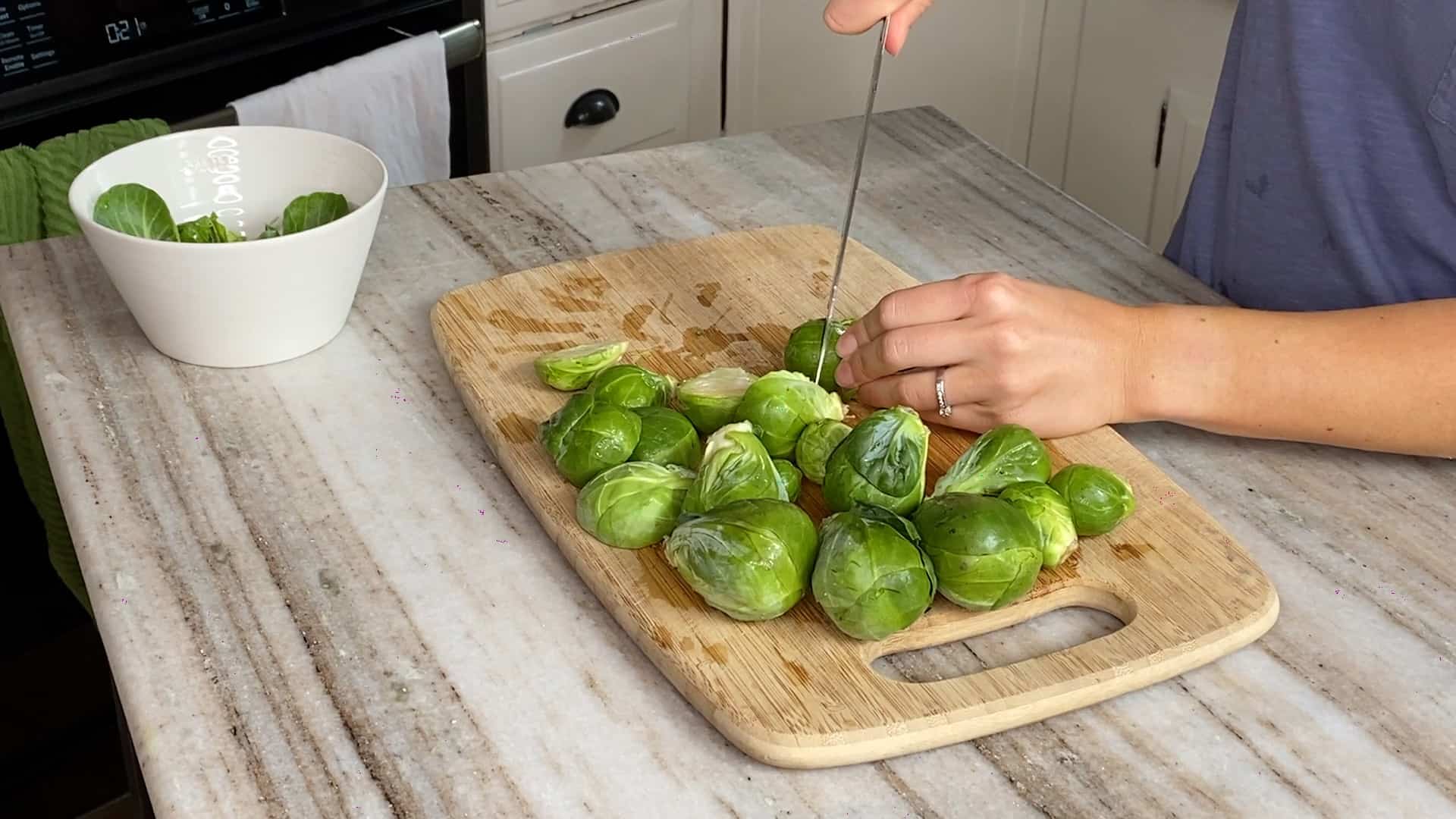woman slicing Brussels sprouts on a bamboo cutting board