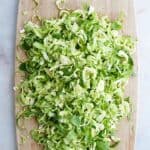 shaved brussels sprouts on a bamboo cutting board on a counter